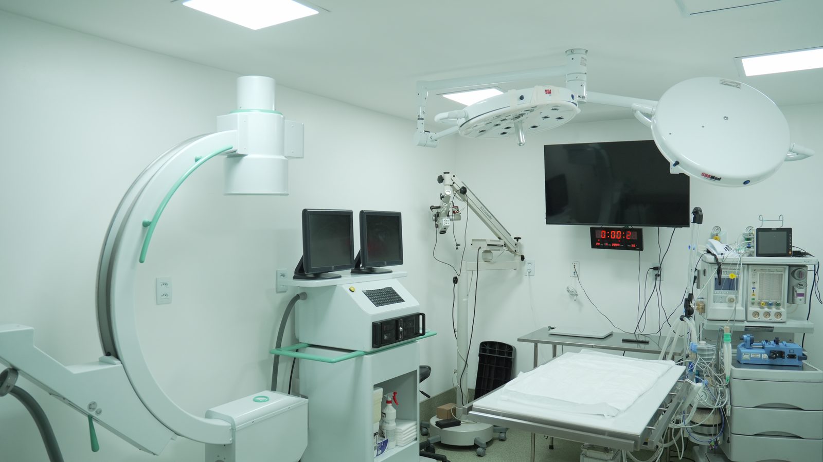 Sala cirúrgica com arco cirúrgico, monitores e foco cirúrgico